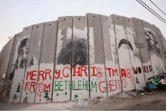 Photograph of the separation wall at Bethlehem with graffiti reading MERRY CHRISTMAS WORLD FROM BETHLEHEM GHETTO