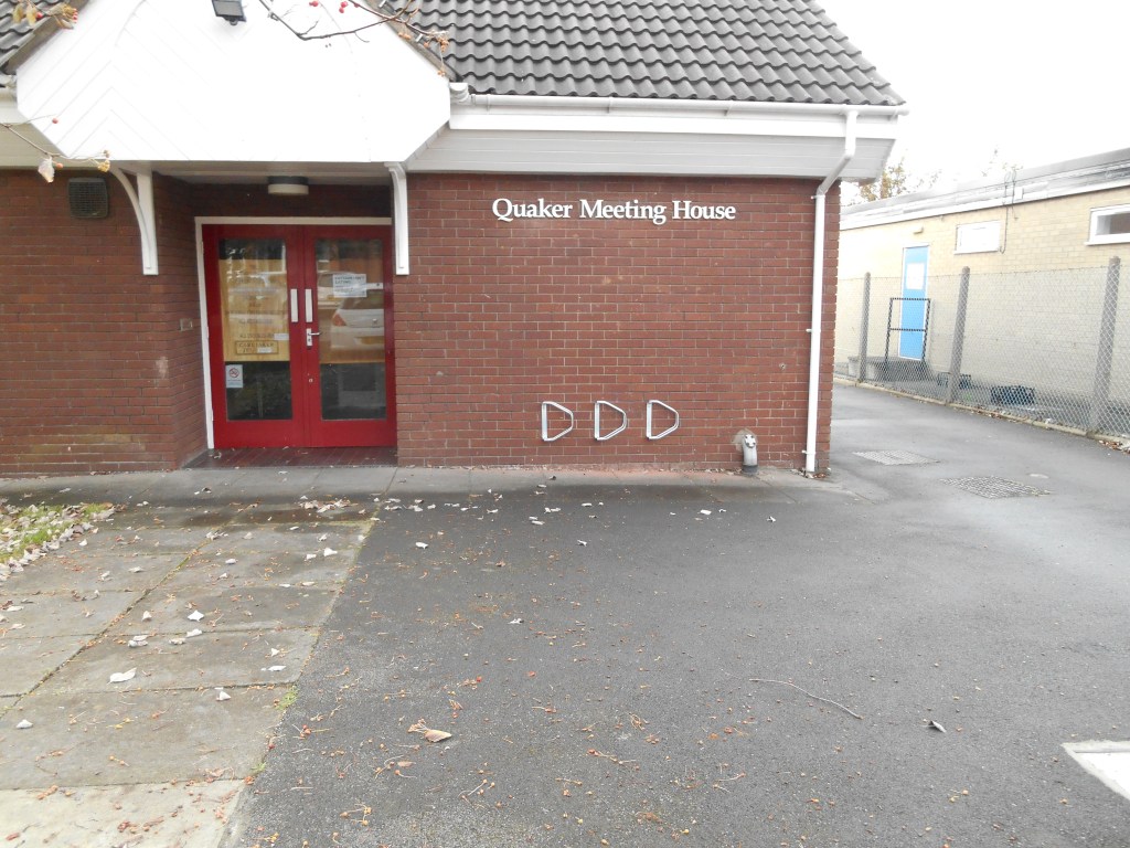 Image shows front of Meeting House with double door, cycle racks and access to rear carpark.